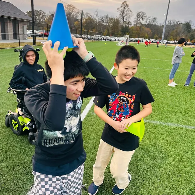Participants smiling during a field activity with colorful cones