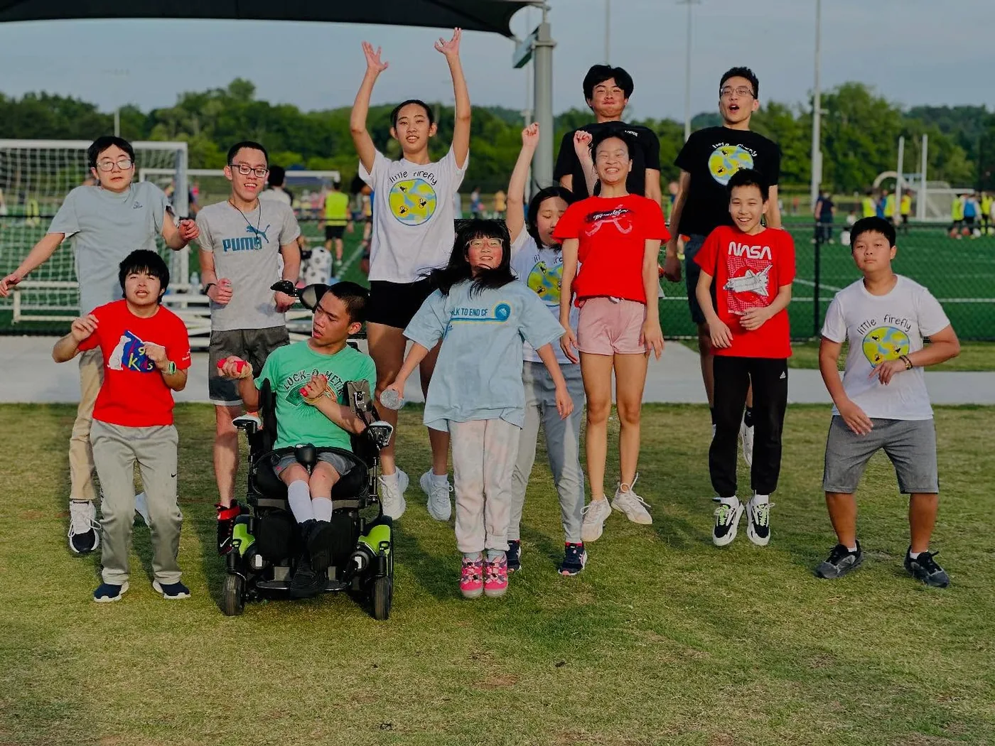 Little Firefly participants and volunteers celebrating together on an outdoor field